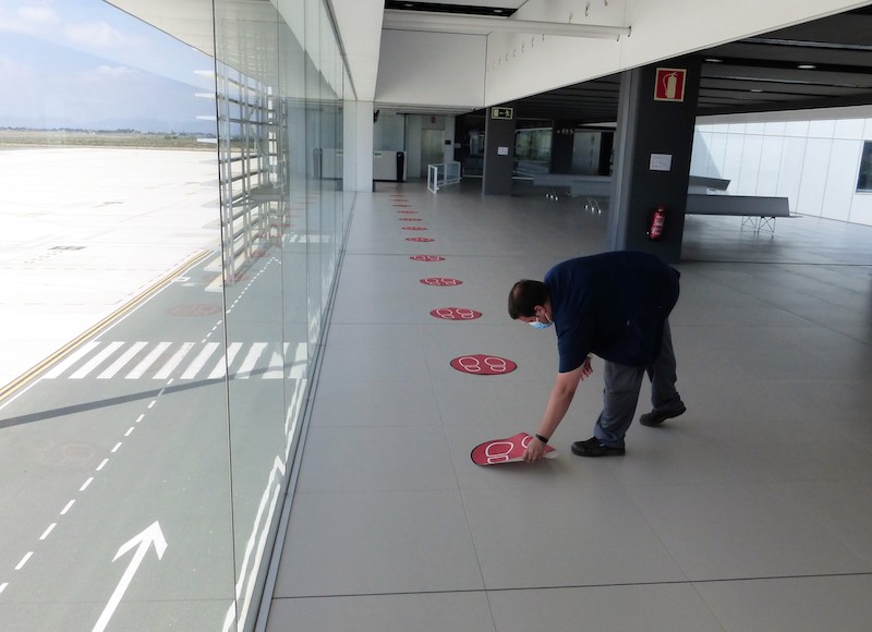 Un empleado de Corvera coloca pegatinas con las distancias mínimas de seguridad para los pasajeros