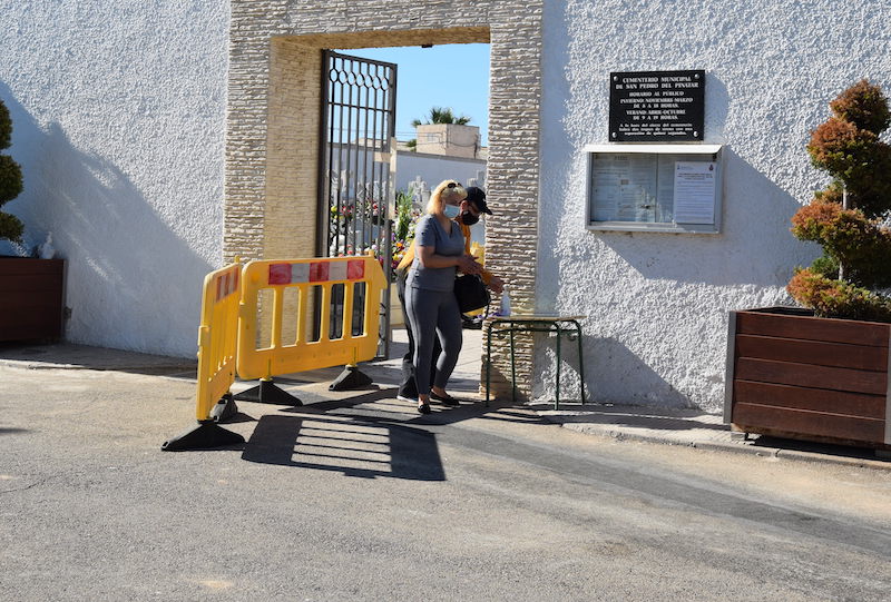 Una mujer sale del cementerio de San Pedro del Pinatar con mascarilla
