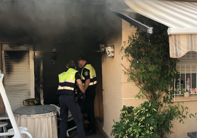 Dos policías tratan de sofocar el incendio en la vivienda