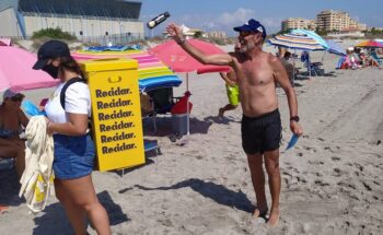 Un bañista arroja un envase en el contenedor móvil de la campaña