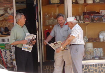 Tres hombres leyendo el Noticiero en papel