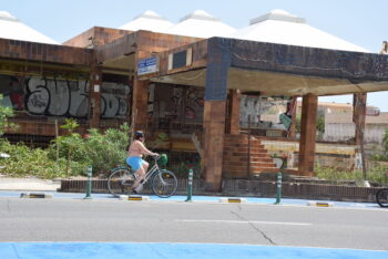 Una ciclista pasa por el frontal de las antiguas galerías comerciales de La Manga