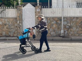 Una anciana camina por La Ribera con un carrito lleno de agua embotellada