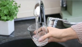 Grifo de agua vertiendo agua potable en un vaso transparente
