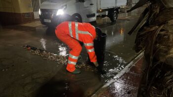 Un operario municipal retira las hojas arrastradas por la lluvia a las rejillas de alcantarillado en Los Alcázares