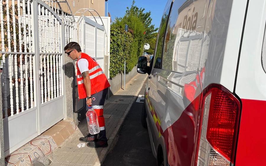 Voluntario de Cruz Roja entregando agua embotellada a una vivienda