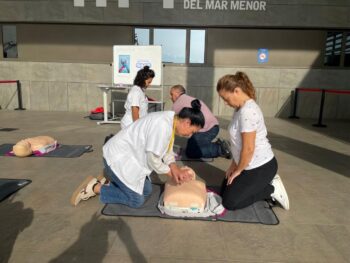 Profesionales enseñan RCP en taller de primeros auxilios en hospital.