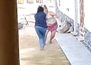 Mujer en conflicto con otra en un espacio exterior, grabado por cámara de seguridad.