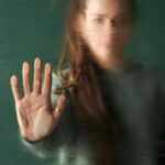Mujer con la mano en un cristal empañado, simbolizando la lucha contra la violencia de género.