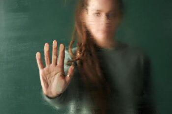 Mujer con la mano en un cristal empañado, simbolizando la lucha contra la violencia de género.