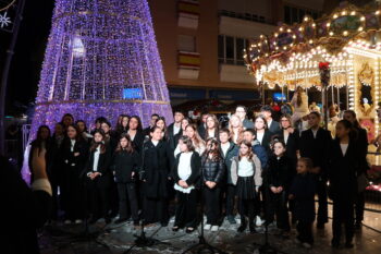Grupo de niños y jóvenes cantando en la Plaza de la Constitución decorada para Navidad