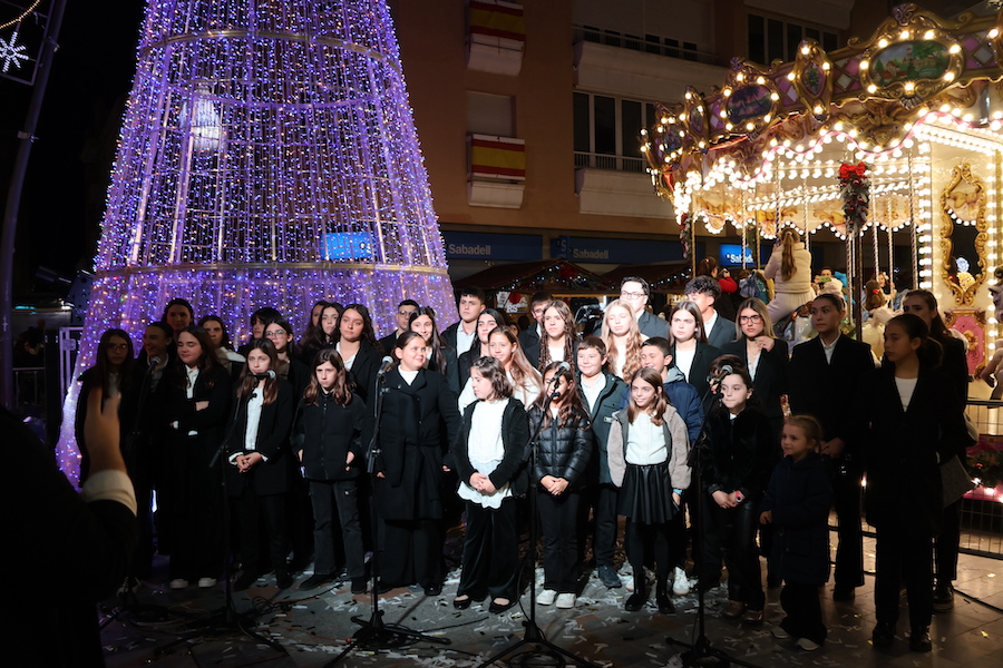Grupo de niños y jóvenes cantando en la Plaza de la Constitución decorada para Navidad