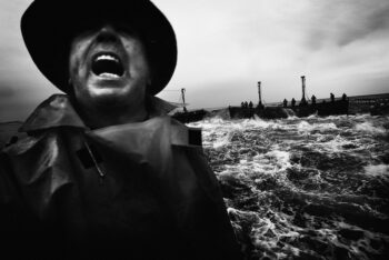 Fotografía en blanco y negro de un hombre gritando en un entorno marino agitado.
