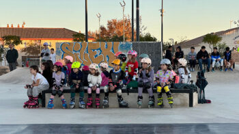 Grupo de niños sentados en un skatepark durante la inauguración.