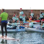 Participantes en kayaks con gorros navideños en Cabo de Palos