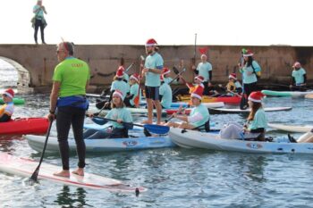 Participantes en kayaks con gorros navideños en Cabo de Palos
