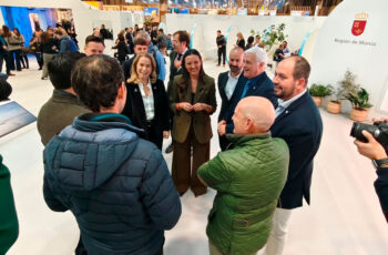 Presentación del calendario náutico en FITUR con varias personas conversando.