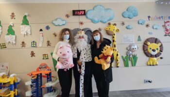 Tres personas en un hospital sosteniendo peluches y sonriendo.