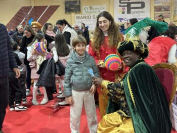Niños interactuando con los Reyes Magos en un evento bajo techo