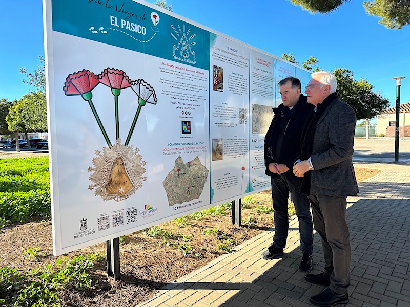 Dos hombres observando un panel informativo sobre rutas de peregrinación en Torre Pacheco.