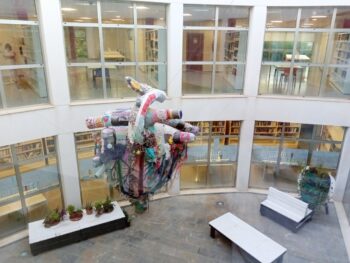 Vista del patio interior de la biblioteca de San Javier con arte y plantas.