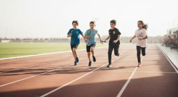 Niños corriendo en una pista de atletismo durante un evento escolar.