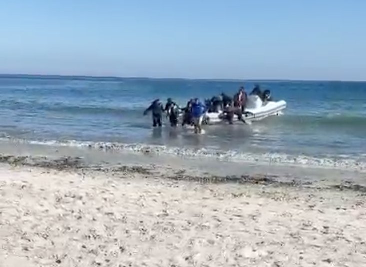 Grupo de personas desembarcando de una patera en la playa de La Torre Derribada