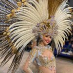 Mujer con disfraz brillante y plumas en el desfile de carnaval