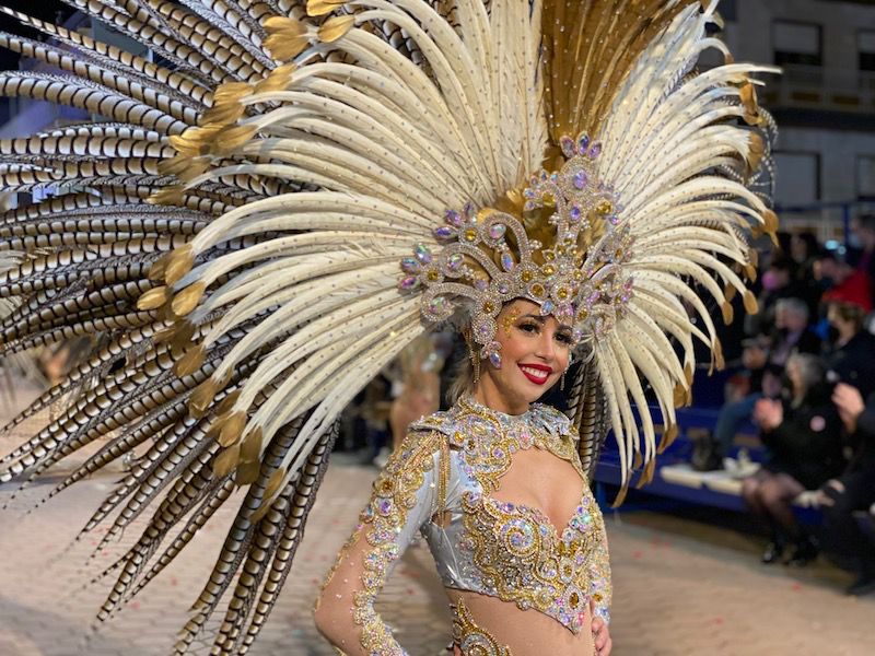 Mujer con disfraz brillante y plumas en el desfile de carnaval