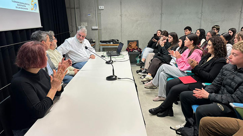 Estudiantes aplaudiendo durante una ponencia sobre investigación histórica.