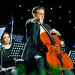 Músico tocando el violonchelo en un concierto con orquesta