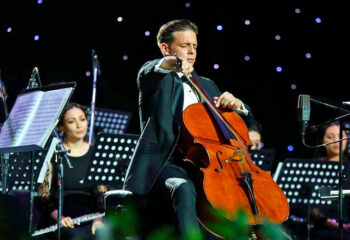 Músico tocando el violonchelo en un concierto con orquesta