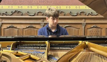 Joven pianista tocando en un piano de cola en un entorno cultural.