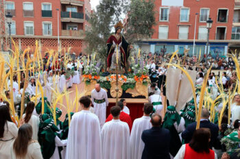 Procesión del Domingo de Ramos con palmas y figura religiosa