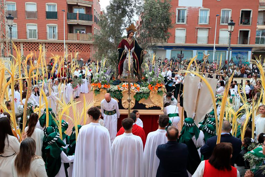 Procesión del Domingo de Ramos con palmas y figura religiosa