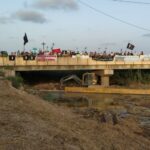 Manifestantes en un puente sosteniendo pancartas sobre el Mar Menor