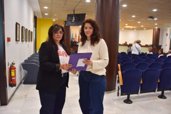 Dos jóvenes sosteniendo una carpeta en un pleno municipal