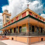 Vista exterior de la Casa Beltrí en Cartagena con palmeras y cielo nublado