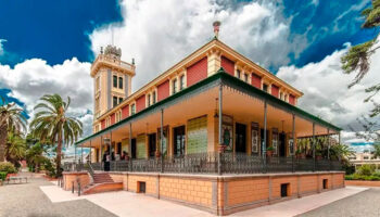 Vista exterior de la Casa Beltrí en Cartagena con palmeras y cielo nublado