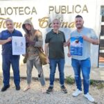 Cuatro personas sosteniendo carteles frente a la Biblioteca Miguel Galindo