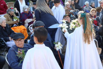 Niños entregando flores a ancianos en procesión de Sábado Santo