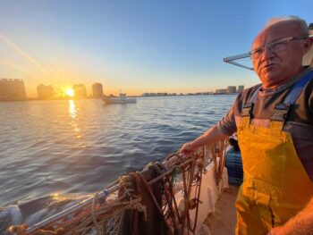 Pescador en el Mar Menor al atardecer con redes de pesca