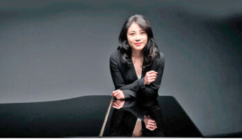 Zee Zee posando junto a un piano en un ambiente elegante