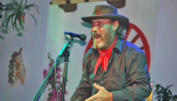 El Cabrero cantando en un escenario con micrófono y vestimenta tradicional