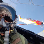 Piloto en cabina con avión acrobático en el fondo