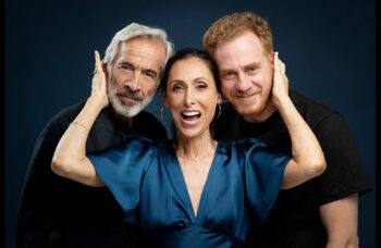 Tres actores posando con sonrisas en un fondo oscuro