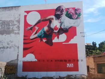 Mural de gran formato en Los Alcázares con un hombre volando y flores.