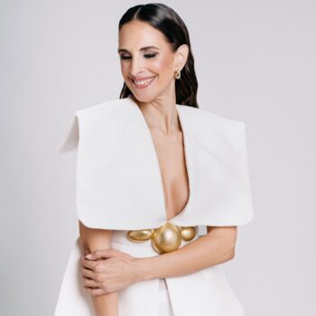 Nuria Fergó sonriente con un vestido blanco y detalles dorados