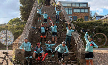 Grupo de ciclistas en una escalera con bicicletas levantadas en señal de victoria