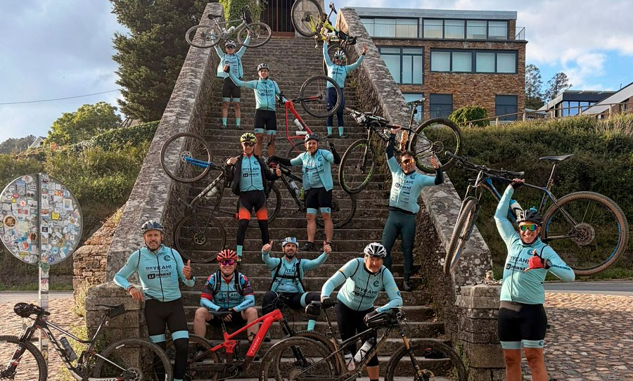 Grupo de ciclistas en una escalera con bicicletas levantadas en señal de victoria